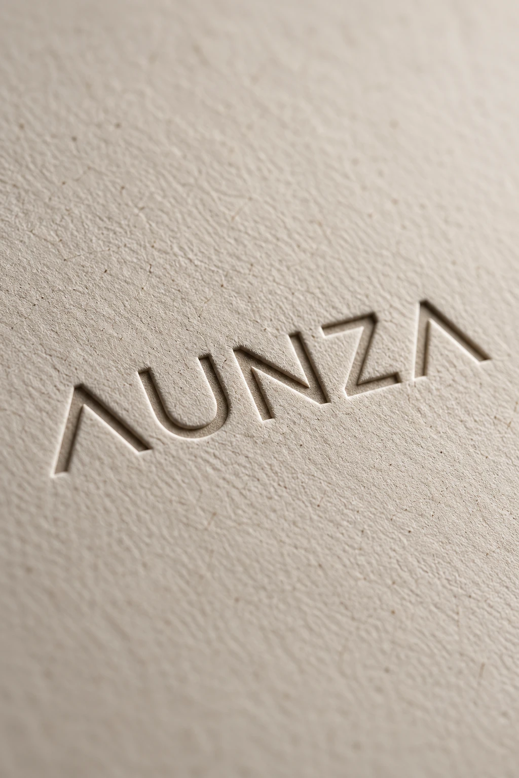 El logotipo de AUNZA en relieve sobre papel grueso de color blanco cálido